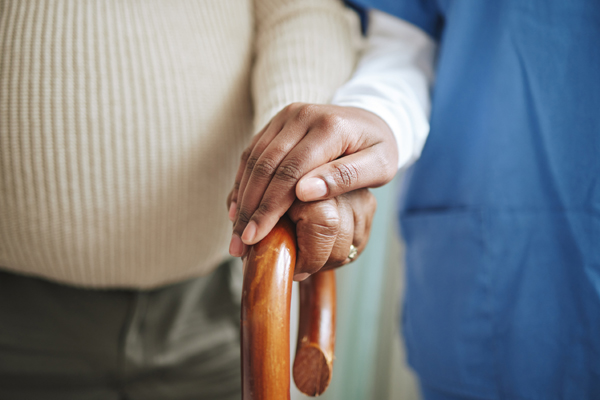 Photo of a caregiver holding the hand of an older man